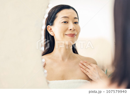 洗面台の鏡を見るミドル女性 107579940