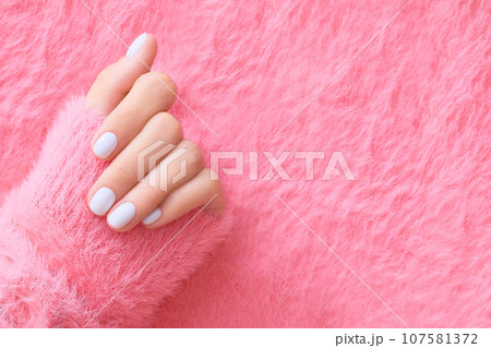 Womans hand with white nail design on pink background. Manicure, pedicure beauty salon concept 107581372