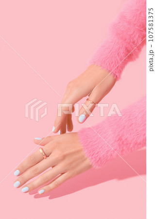 Womans hands with white manicure on pink background 107581375
