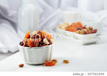 Dried fruits and assorted nuts on a white table. Dried fruits and assorted nuts on a white table. 107581840