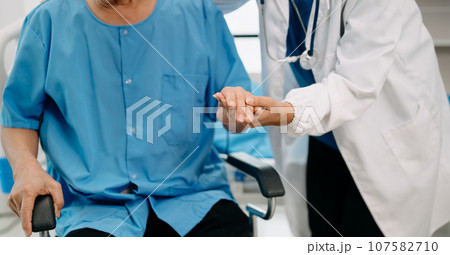 Asian physiotherapist helping elderly man patient stretching arm during exercise correct with dumbbell in hand during training hand in bed in clinic Asian physiotherapist helping elderly man patient stretching arm during exercise correct with dumbbell in hand during training hand in bed in clinic 107582710