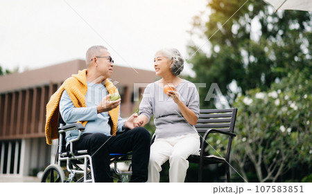 Asian senior couple having a good time. They laughing and smiling while sitting outdoor at the park. Lovely senior couple. 107583851