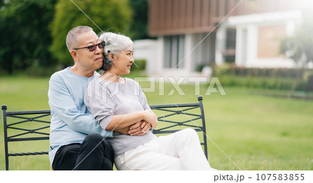 Asian senior couple having a good time. They laughing and smiling while sitting outdoor at the park. Lovely senior couple. 107583855