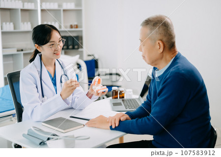 Concentrated dentist sitting at table with jaw samples tooth model and working with tablet and laptop in dental office dental clinic. medical doctor working 107583912
