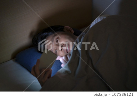 ベッドでスマホを使う男性 107586121