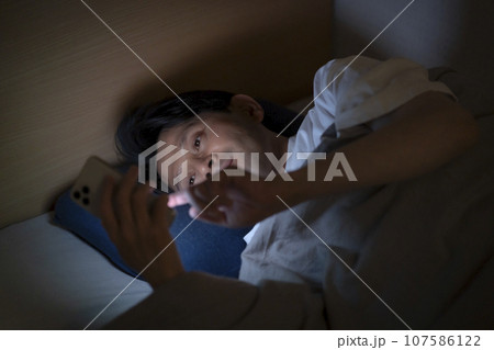ベッドでスマホを使う男性 ベッドでスマホを使う男性 107586122