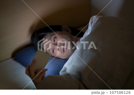 ベッドでスマホを使う男性 107586126