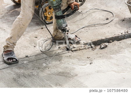 Construction worker using jackhammer drilling concrete surface 107586480