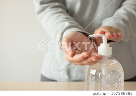 Woman using alcohol sanitizer gel rub for cleaning hand COVID-19 corona virus prevention concept 107586869