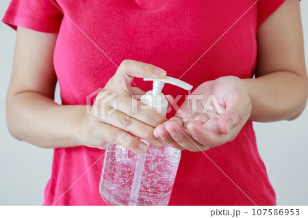 Woman using alcohol sanitizer gel rub for cleaning hand COVID-19 corona virus prevention concept 107586953