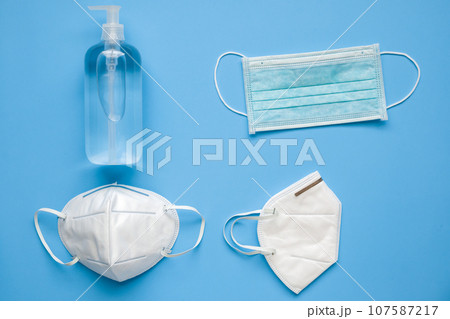 Alcohol hand sanitizer gel bottle with KN95 surgical face mask on blue background protection against COVID-19 coronavirus. Healthcare and medical concept Alcohol hand sanitizer gel bottle with KN95 surgical face mask on blue background protection against COVID-19 coronavirus. Healthcare and medical concept 107587217