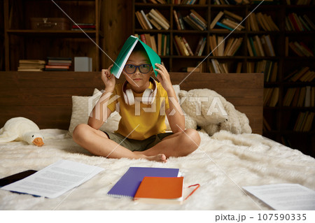 Cute school boy having difficulties with homework sitting in bed Cute school boy having difficulties with homework sitting in bed 107590335