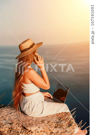 Freelance happy woman typing on her laptop, enjoying the picturesque sea view, highlighting the idea of working remotely with a relaxed and pleasant atmosphere. Freelance happy woman typing on her laptop, enjoying the picturesque sea view, highlighting the idea of working remotely with a relaxed and pleasant atmosphere. 107591091