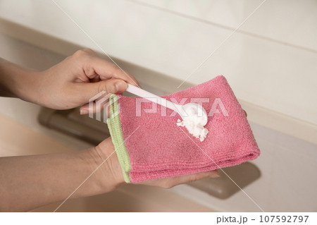 ピンクのタオルに重曹をのせる女性作業員の手元 ピンクのタオルに重曹をのせる女性作業員の手元 107592797