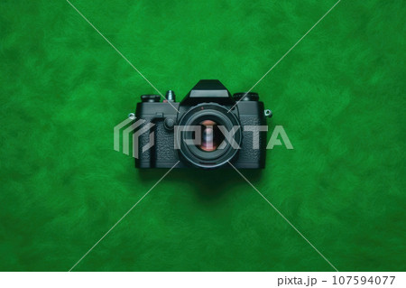 Top View of Sleek Black Camera on Vibrant Green Background 107594077