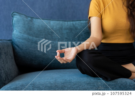Portrait of healthy Asian woman meditating and exercise pose yoga on the sofa in morning. Zen relaxation and mindfulness lifestyle, Concept of indoor workout for good healthy and breathing practice. Portrait of healthy Asian woman meditating and exercise pose yoga on the sofa in morning. Zen relaxation and mindfulness lifestyle, Concept of indoor workout for good healthy and breathing practice. 107595324