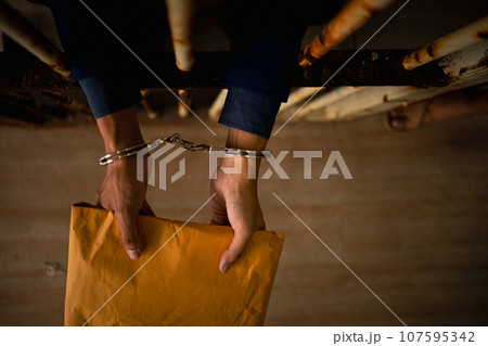 Asian businessmen hold documents and wear handcuffs in jail after arrest because corruption and defrauding insurance. Concept of punishment for crime fraudulent, victim criminal, justice protection. 107595342