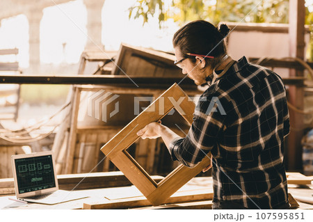 Carpenter Joiner man making wooden furniture in wood workshop professional high skill real authentic handcrafted working people. 107595851