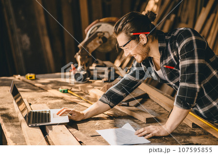 Carpenter man using modern technology computer laptop software aided sketch design new wooden furniture project Carpenter man using modern technology computer laptop software aided sketch design new wooden furniture project 107595855