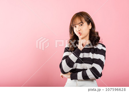 Woman making finger on lips mouth silent quiet gesture, Happy Asian beautiful young female marking silence for stop quiet, mute studio shot isolated on pink background with copy space 107596628