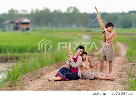Asian woman look like older sister with traditional cloth sit close to young boy with one stand 107598419