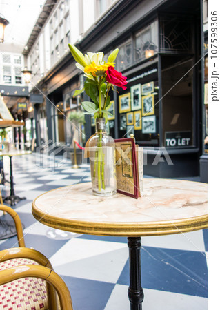 カフェの店先に置かれたテーブルに飾られた花 ウエールズの街カーディフのアーケードにて カフェの店先に置かれたテーブルに飾られた花 ウエールズの街カーディフのアーケードにて 107599306
