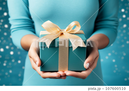 Beautiful faceless woman in a blue dress with a blue gift box close-up 107600510