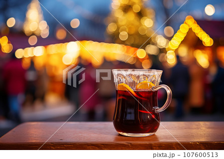 Traditional mulled wine in a glass mug on an empty tabletop at Christmas street fair with bright lights and festive atmosphere 107600513
