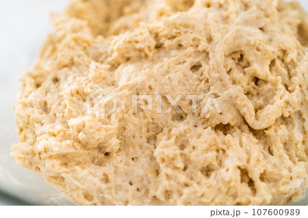 Mixing wet and dry ingredients with a hand whisk in a glass mixing bowl to bake lemon poppy seed muffins. 107600989