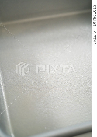 Greasing metal square baking pan to bake sweets. Greasing metal square baking pan to bake sweets. 107601015