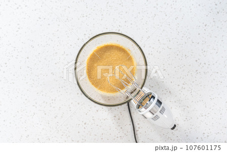 Flat lay. Mixing ingredients with a hand mixer in a large mixing bowl to bake dulce de leche cupcakes. Flat lay. Mixing ingredients with a hand mixer in a large mixing bowl to bake dulce de leche cupcakes. 107601175