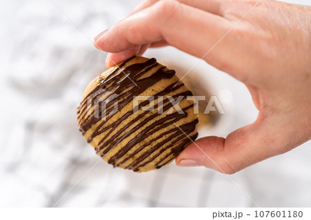 Freshly baked banana cookies with chocolate drizzle on a kitchen counter. Freshly baked banana cookies with chocolate drizzle on a kitchen counter. 107601180