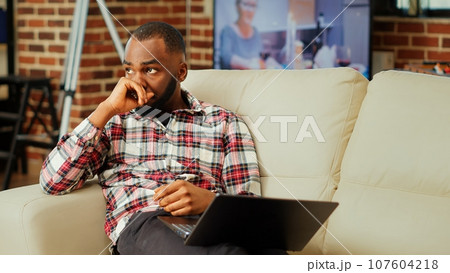 Stressed remote worker looking for creative ideas for project, struggling to figure out problem solutions. Freelancer teleworker over thinking, trying to solve tasks in apartment personal office Stressed remote worker looking for creative ideas for project, struggling to figure out problem solutions. Freelancer teleworker over thinking, trying to solve tasks in apartment personal office 107604218