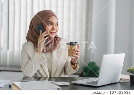 Young muslim millennial businesswoman in brown hijab headscarf working with laptop computer at the modern office. Young muslim millennial businesswoman in brown hijab headscarf working with laptop computer at the modern office. 107605958