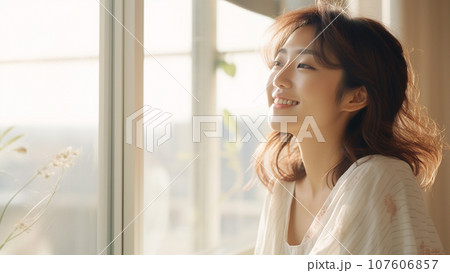 明るい窓辺で微笑む20代～30代の日本人女性のポートレート 107606857