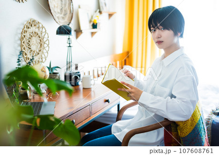 自宅の部屋で読書をするショートヘアの女性モデルのポートレイト 自宅の部屋で読書をするショートヘアの女性モデルのポートレイト 107608761