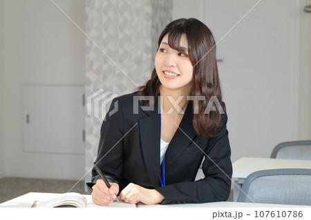 机に向かい手帳に書き込む女性の写真素材 [107610786] - PIXTA
