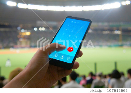 野球場の観客席でスマホで通話する人 107612662