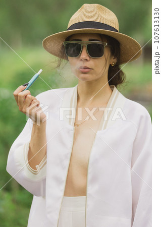 beautiful woman smoking electronic cigarette in street. 107613130