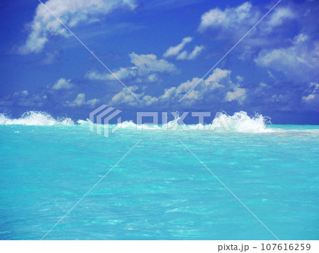 エメラルドグリーンの浅瀬で崩れる波頭 107616259