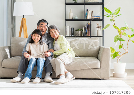 リビングでくつろぐ孫娘とシニアの夫婦 107617209
