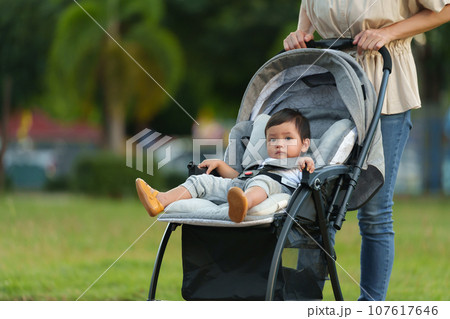 mother pushing infant baby stroller and walking in park mother pushing infant baby stroller and walking in park 107617646