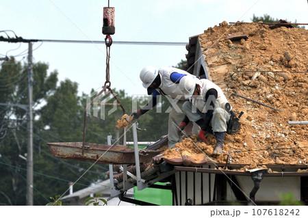 屋根瓦の葺き替え工事 手作業で古い瓦の撤去作業 屋根瓦の葺き替え工事 手作業で古い瓦の撤去作業 107618242