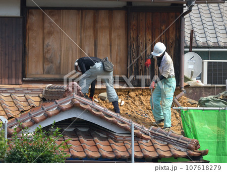 屋根瓦の葺き替え工事 手作業で古い瓦の撤去作業 屋根瓦の葺き替え工事 手作業で古い瓦の撤去作業 107618279