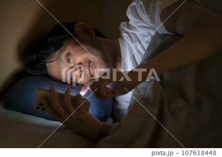 ベッドでスマホを使う男性 107618448