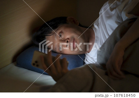 ベッドでスマホを使う男性 107618450