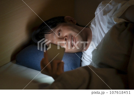 ベッドでスマホを使う男性 ベッドでスマホを使う男性 107618451