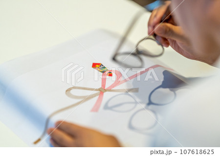 老眼鏡をかけてのし紙に書き入れる準備 107618625