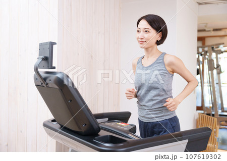 スポーツジムのランニングマシンで運動する女性（健康・ダイエット） 107619302