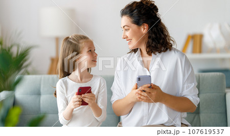 Young mother and daughter using phones 107619537